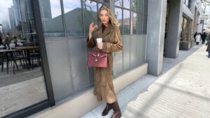 tendenza camoscio inverno 2026 - modella con cappotto in camoscio marrone e borsa burgundy